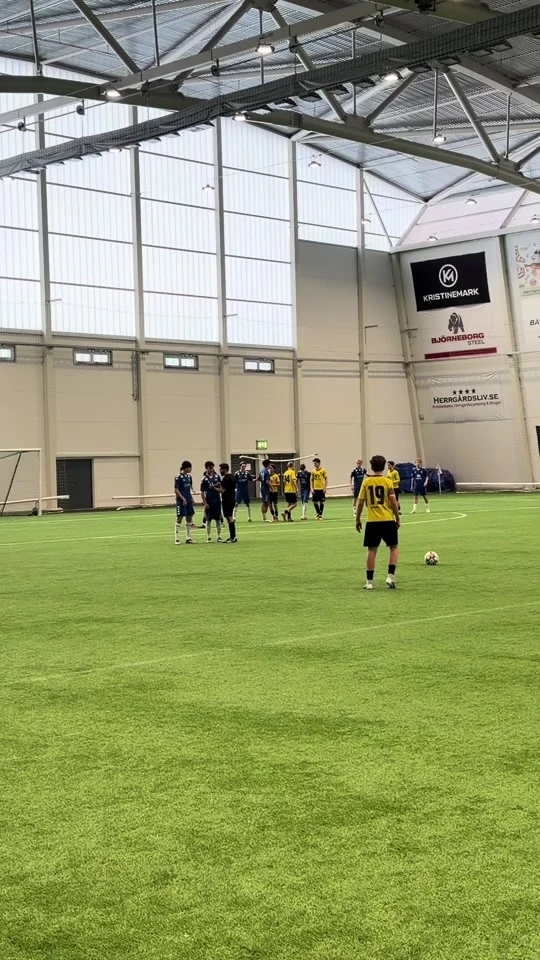 Fotbollsmatch på inomhusplan med domare nära spelet
